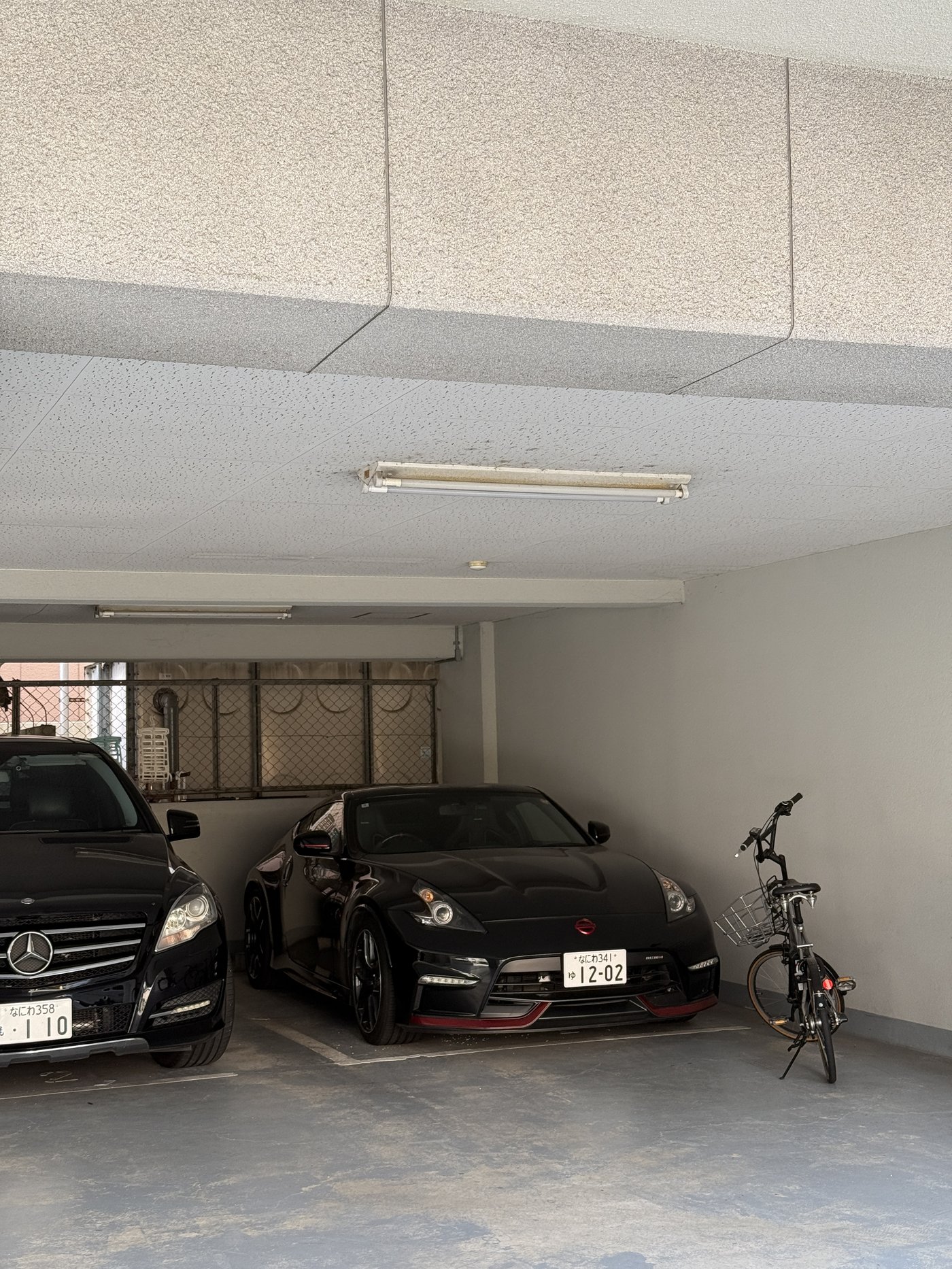 Černý Mercedes a Nissan 370Z Nismo v podzemní garáži v Ósace