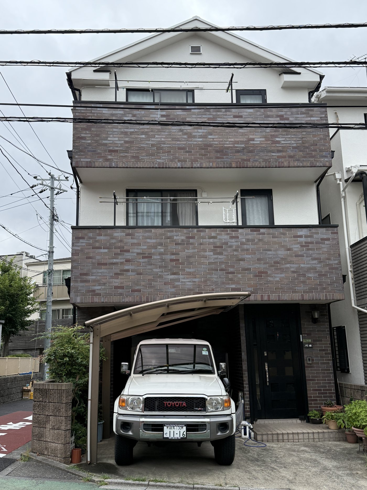Bílý Toyota Land Cruiser 70 pod carportem rodinného domu