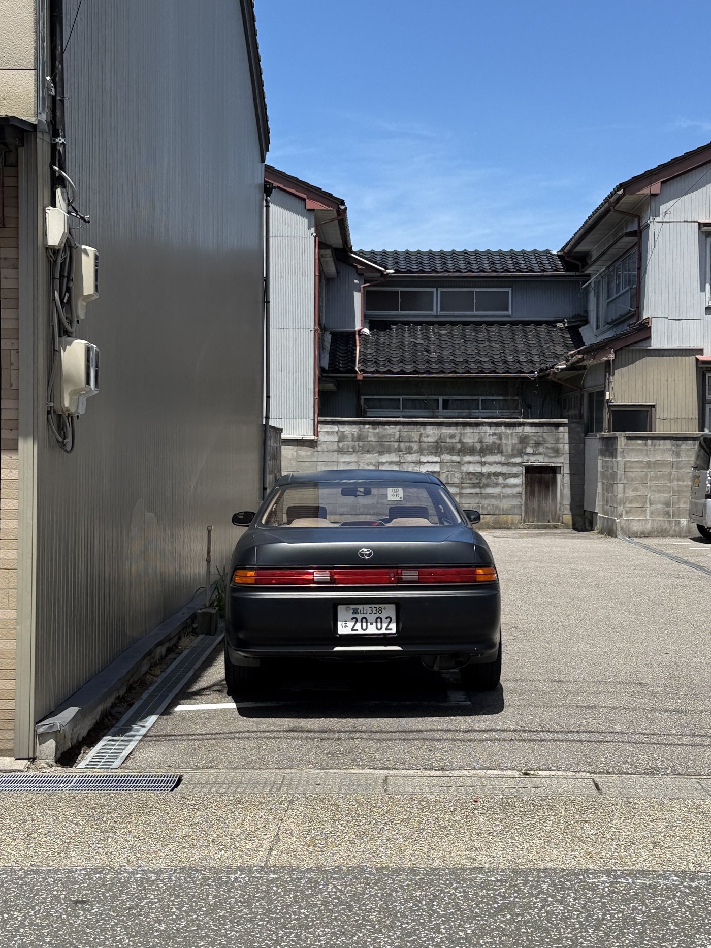 Černý Toyota Soarer zaparkovaný v uličce mezi domy
